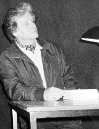 Giordano sitzt am Tisch mit Buch und Lampe, Schwarzweißaufnahme