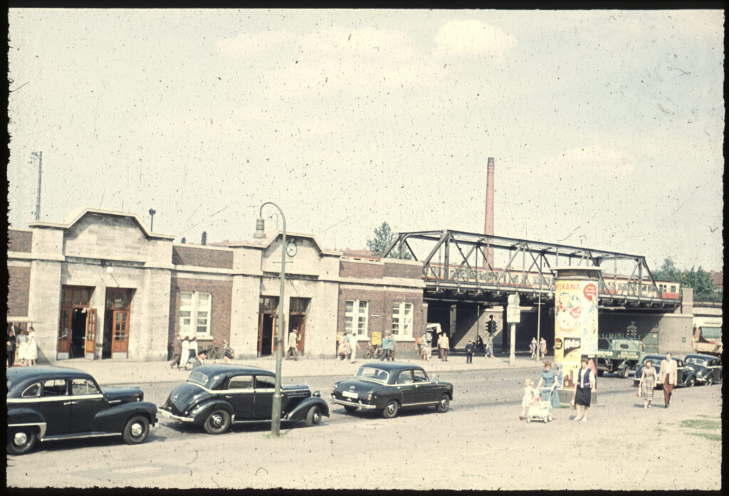 Eingang Bahnhof Barmbek mit Brücke, alten Autos und Fußgängern auf der Straße